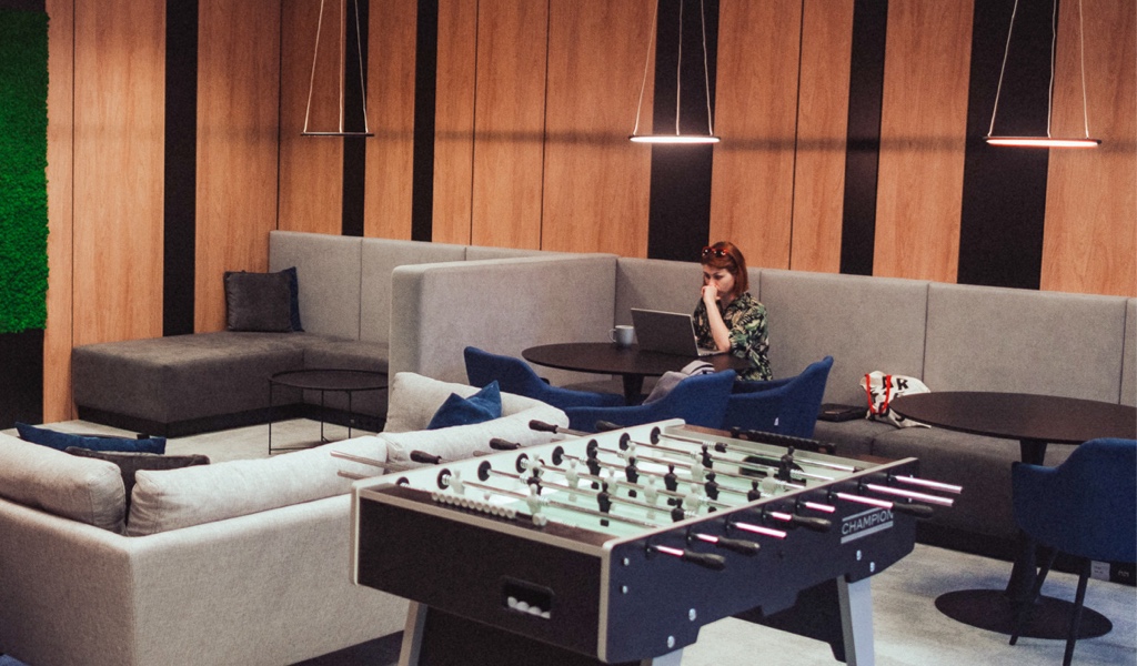 Lounge with table football and a colleague working on her laptop