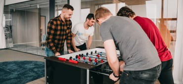 Four team members playing table football 