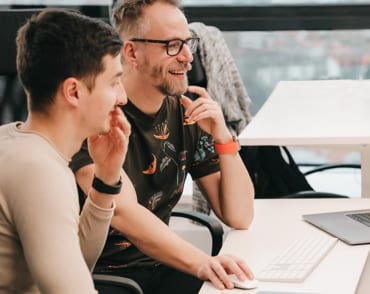 Two team members collaborating on their laptops