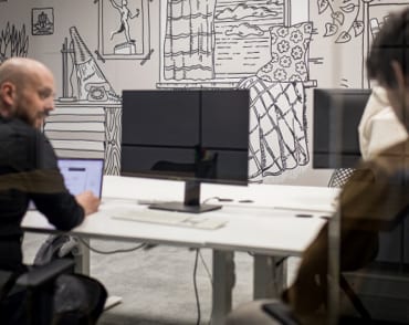 Office wall with custom illustrations and two team members discussing work