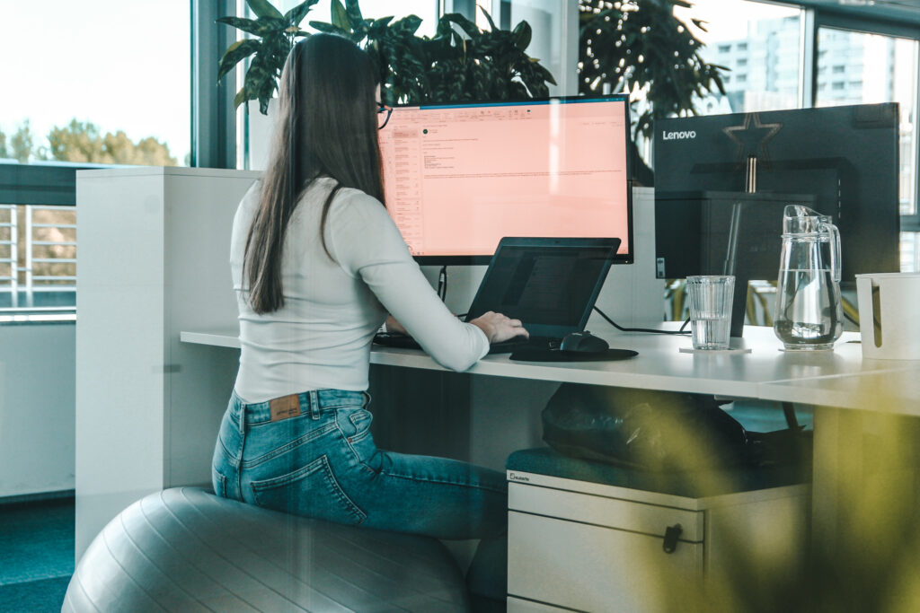 Woman sitting on a gym ball working on a laptop.