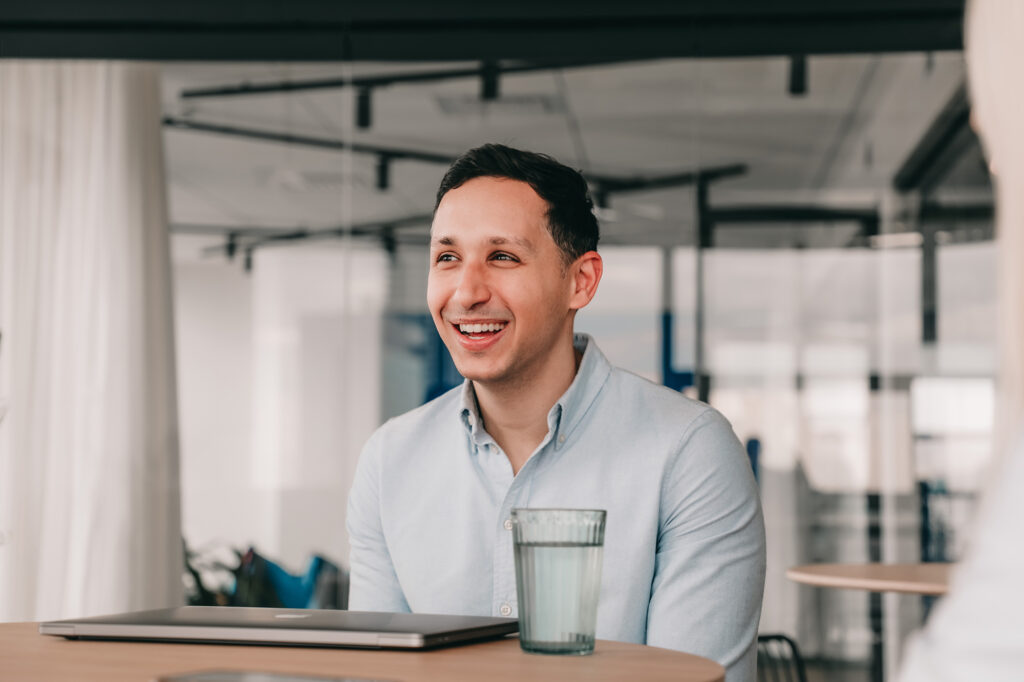 Data Engineer smiling at the table with his laptop.