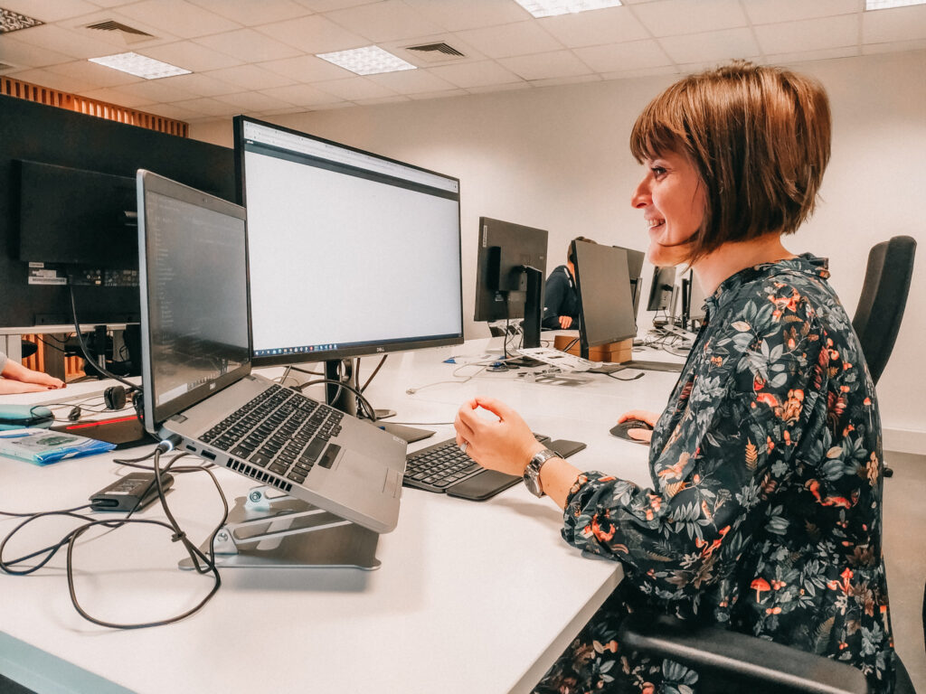 Female QA Tester smiling and working in the office.