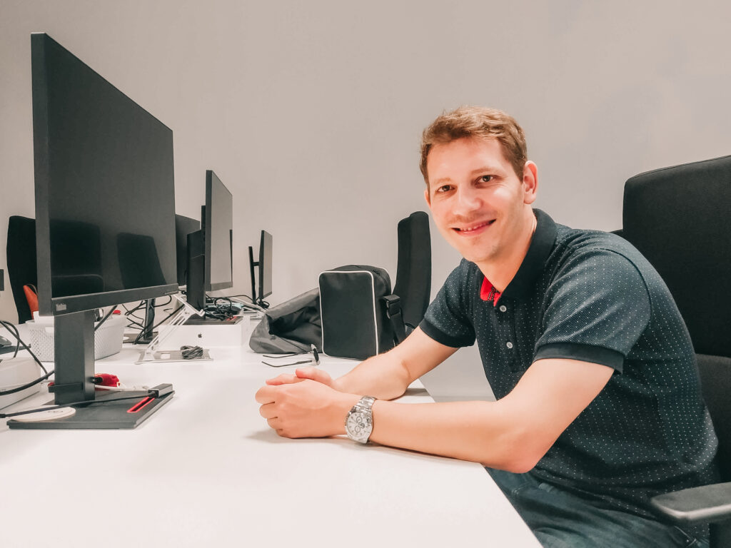 Software Engineer smiling at his desk.