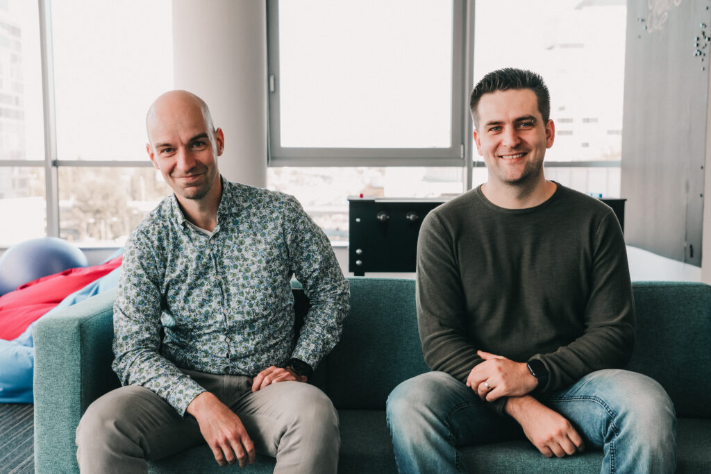 Two developers sitting on a sofa and smiling.