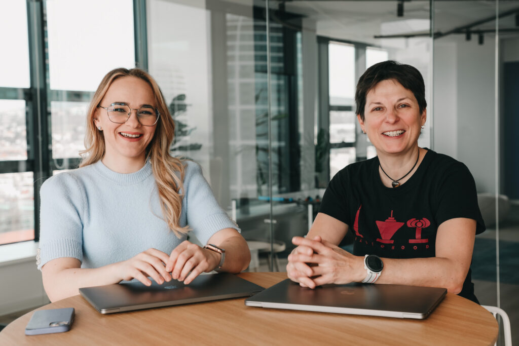 two female software engineers sitting with laptops and smiling