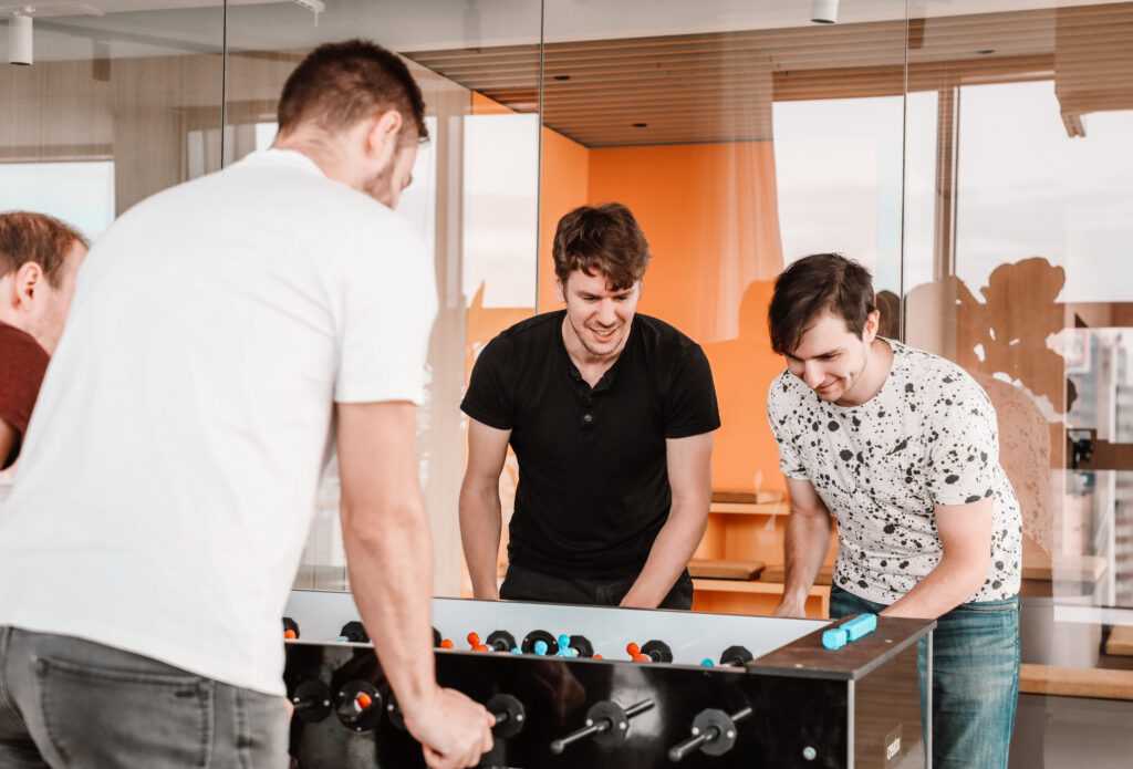 four male colleagues playing table football