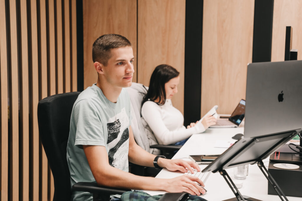 a male and female colleagues working on computers side by side