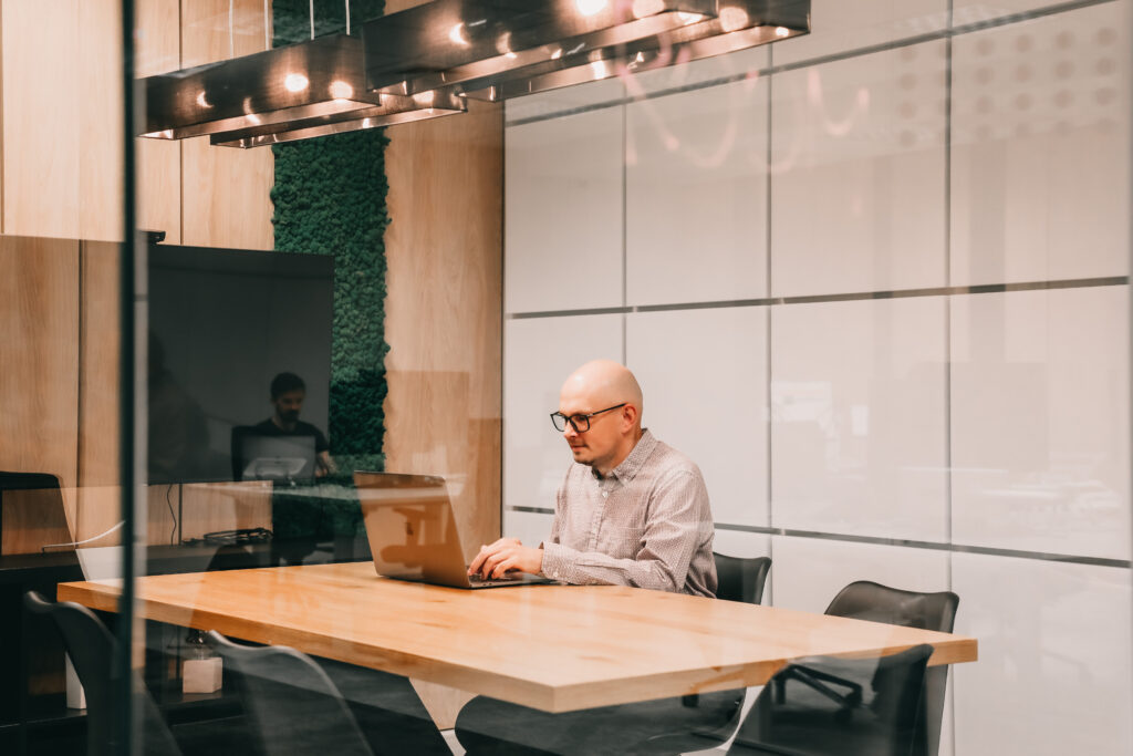 a male software engineer working on a laptop in a meeting room
