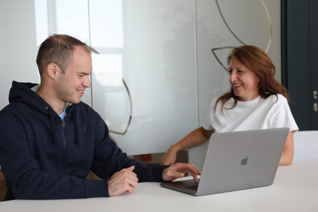 male and female colleagues discussing work over a laptop and smiling