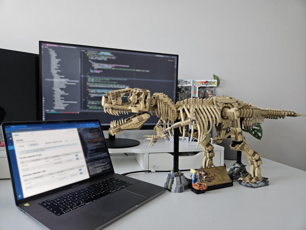 lego dinosaur next to the laptop and big computer screen