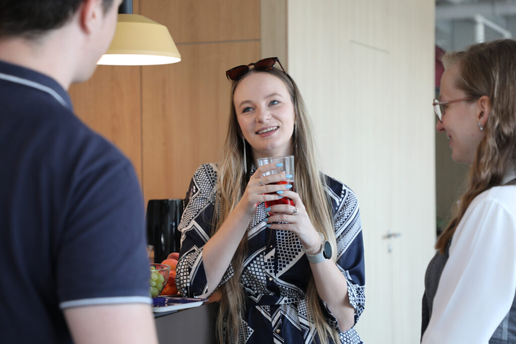 portrait of a female qa analyst during office breakfast with two colleagues in the background