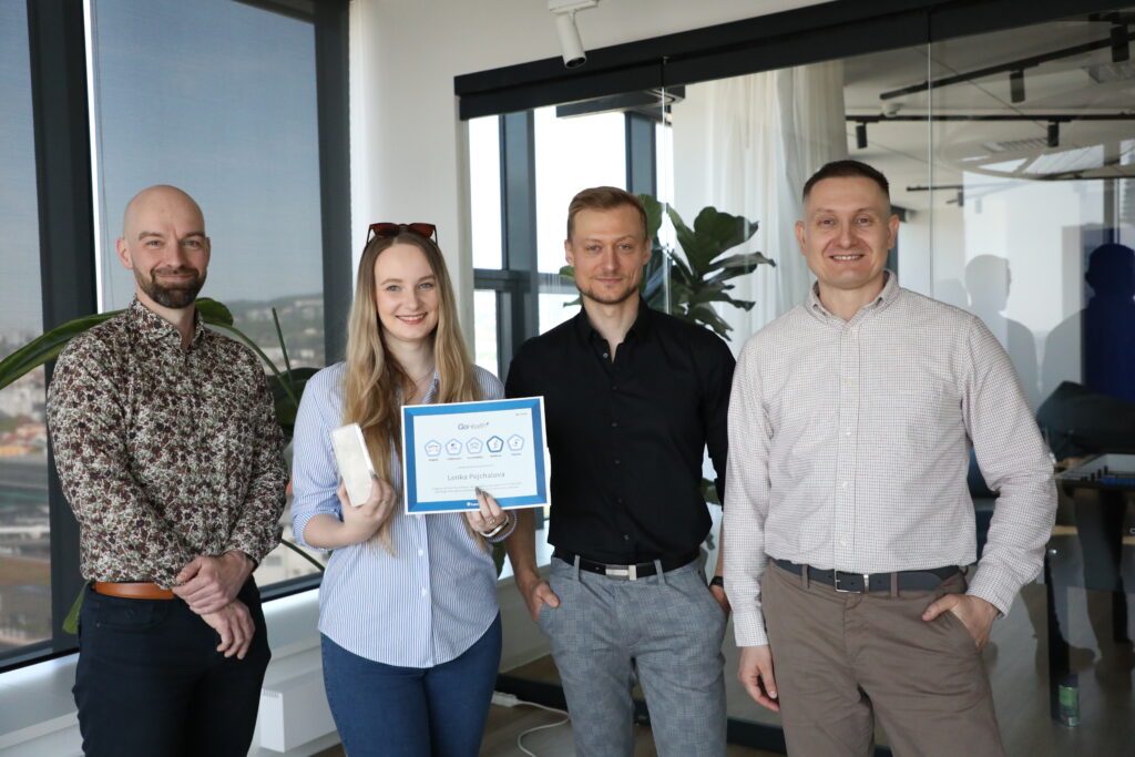 female qa analyst holding a prize standing next to her three software developer colleagues