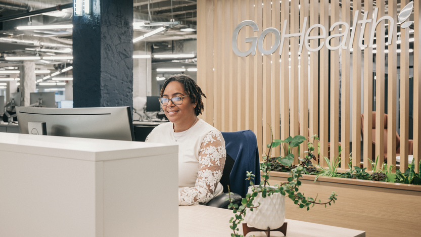 a female receptionist working on a laptop with company logo in the background