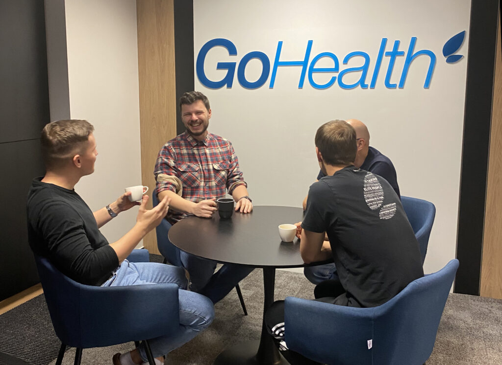 four male colleagues having coffee and laughing at the office kitchen table